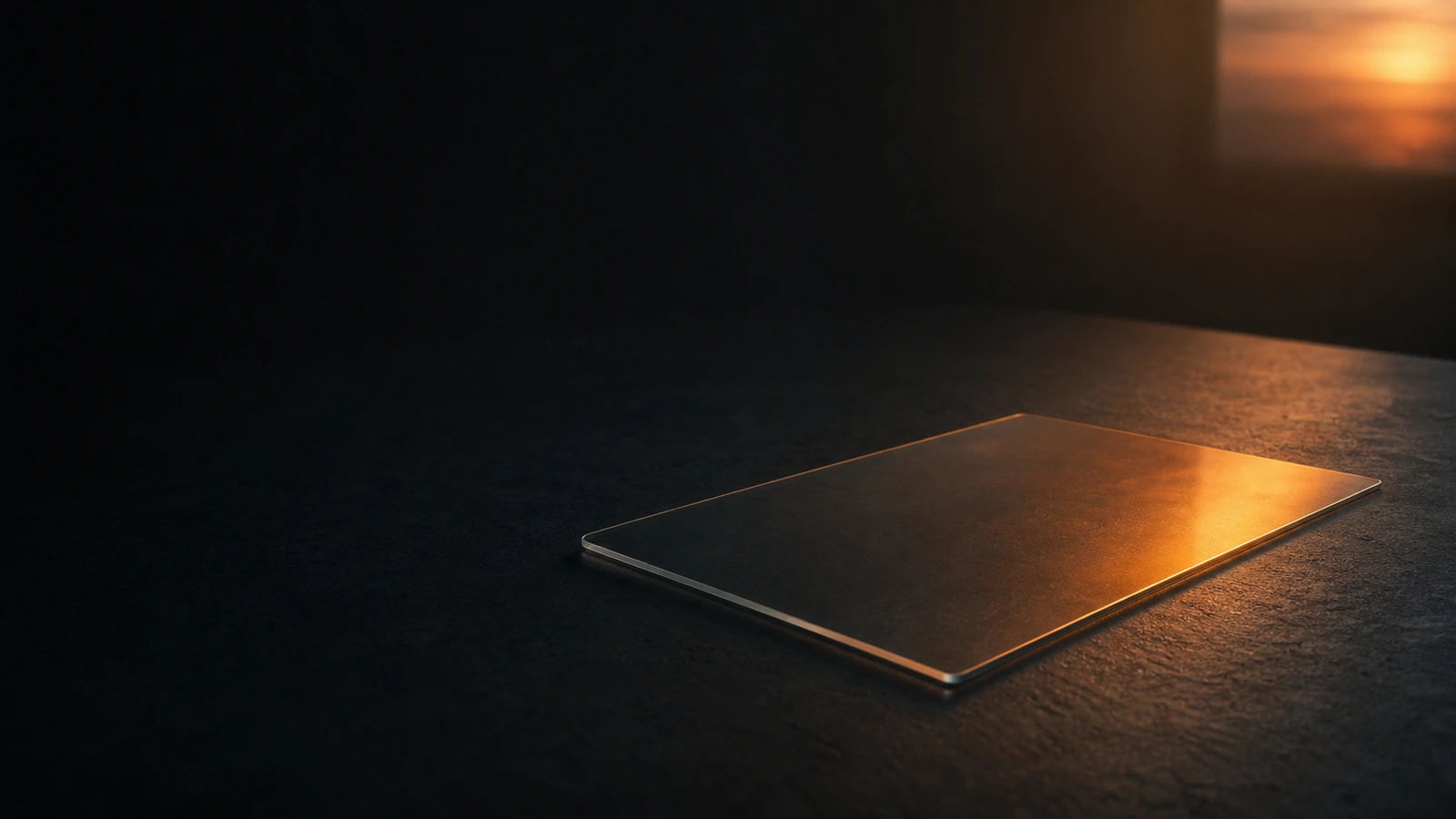 A dimmed window-like glass panel on a dark surface with soft warm orange glow fading at the edges — sense of ending / sunset.