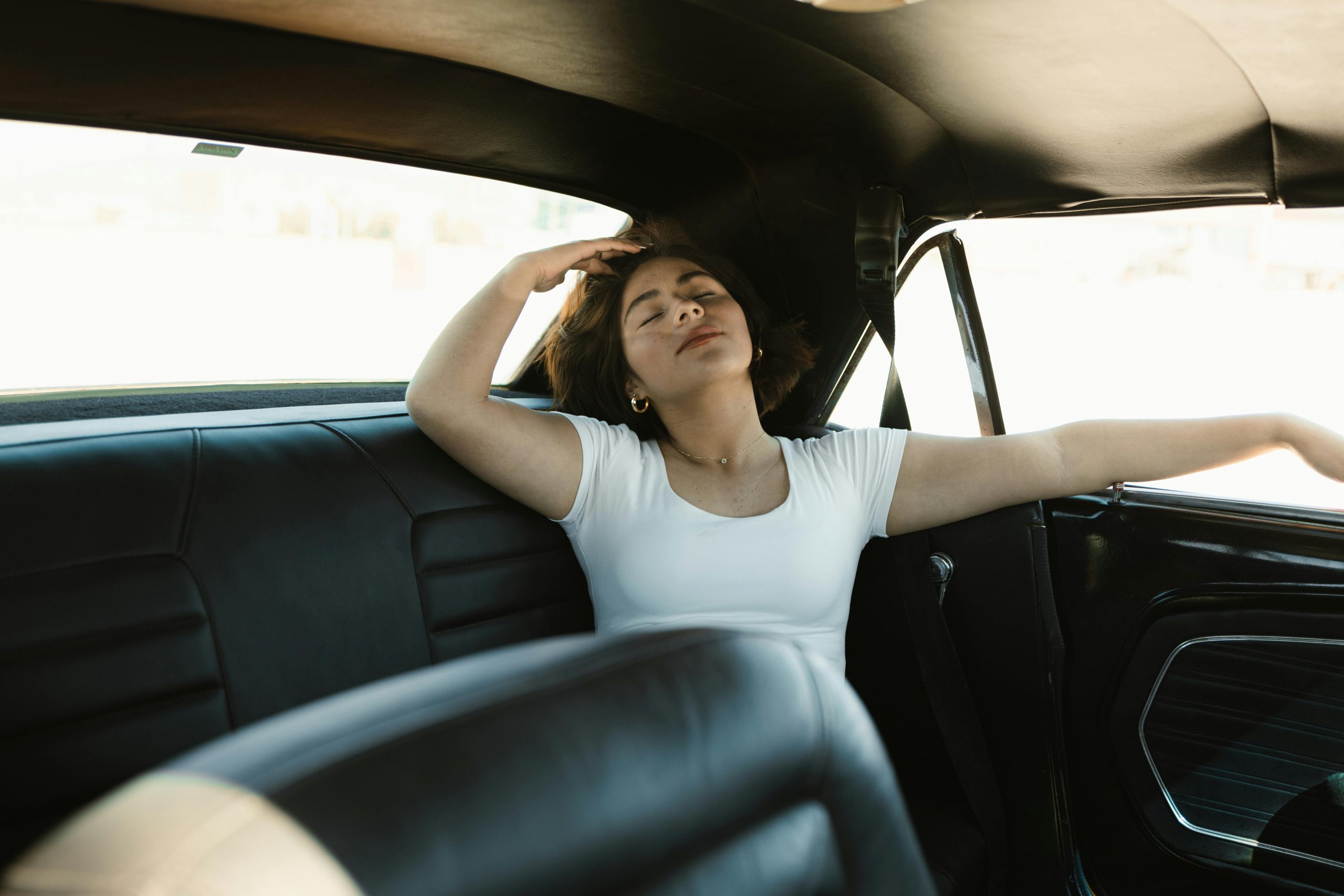 Woman relaxing in the backseat of a vintage car in Los Angeles.