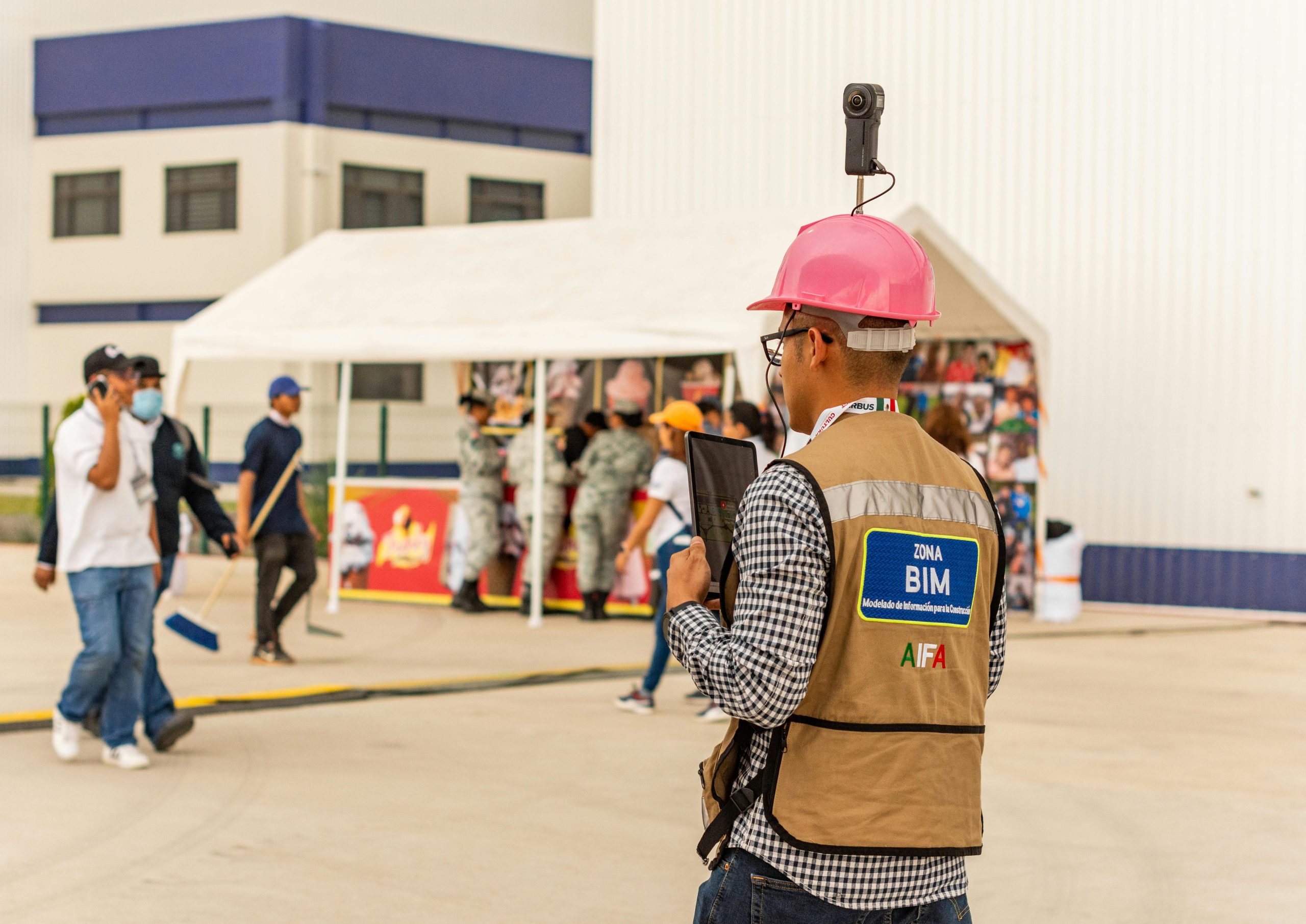 A construction worker with a tablet and camera inspects a site, using modern technology for documentation.