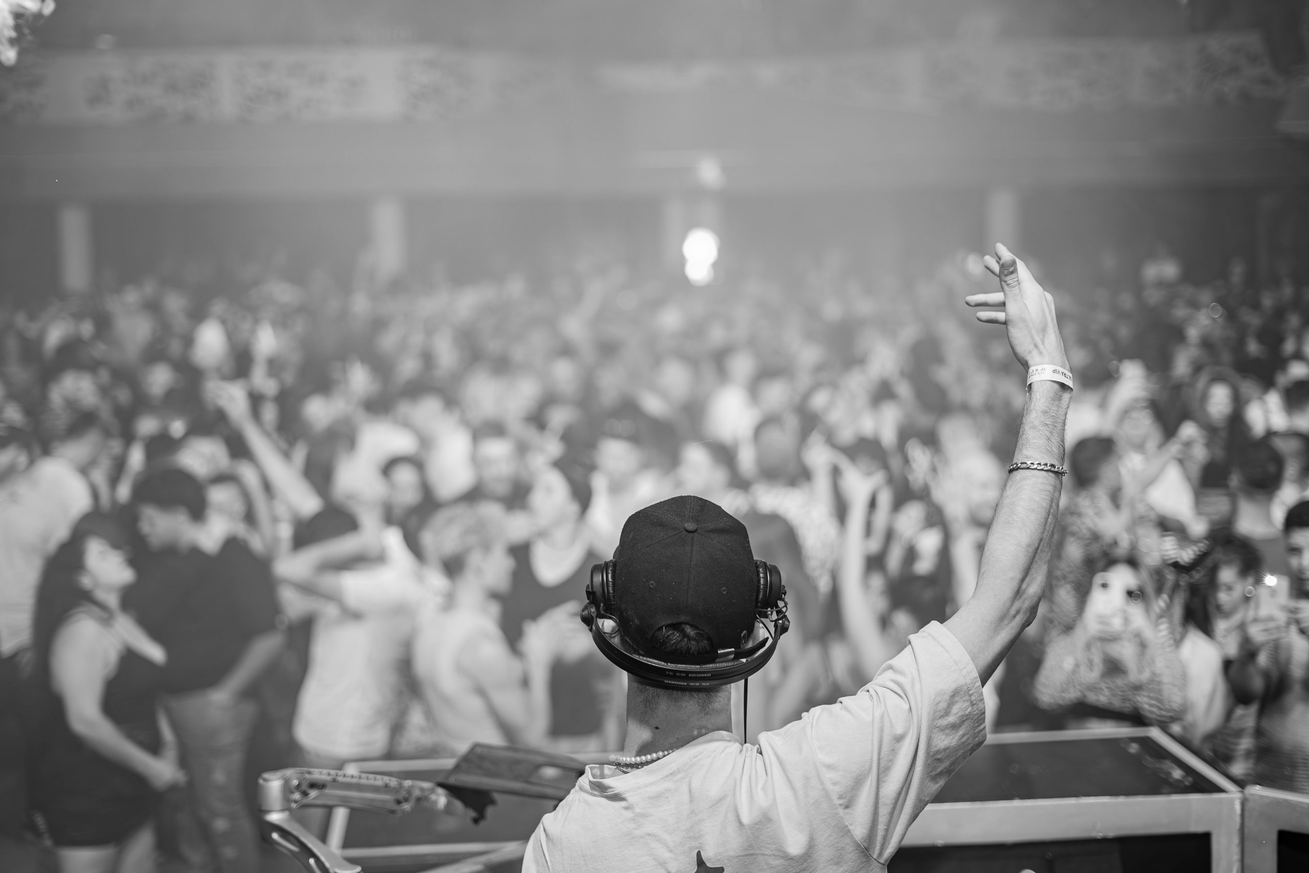 DJ in control, hyping up a large crowd at a lively nightclub event, creating an electrifying atmosphere.