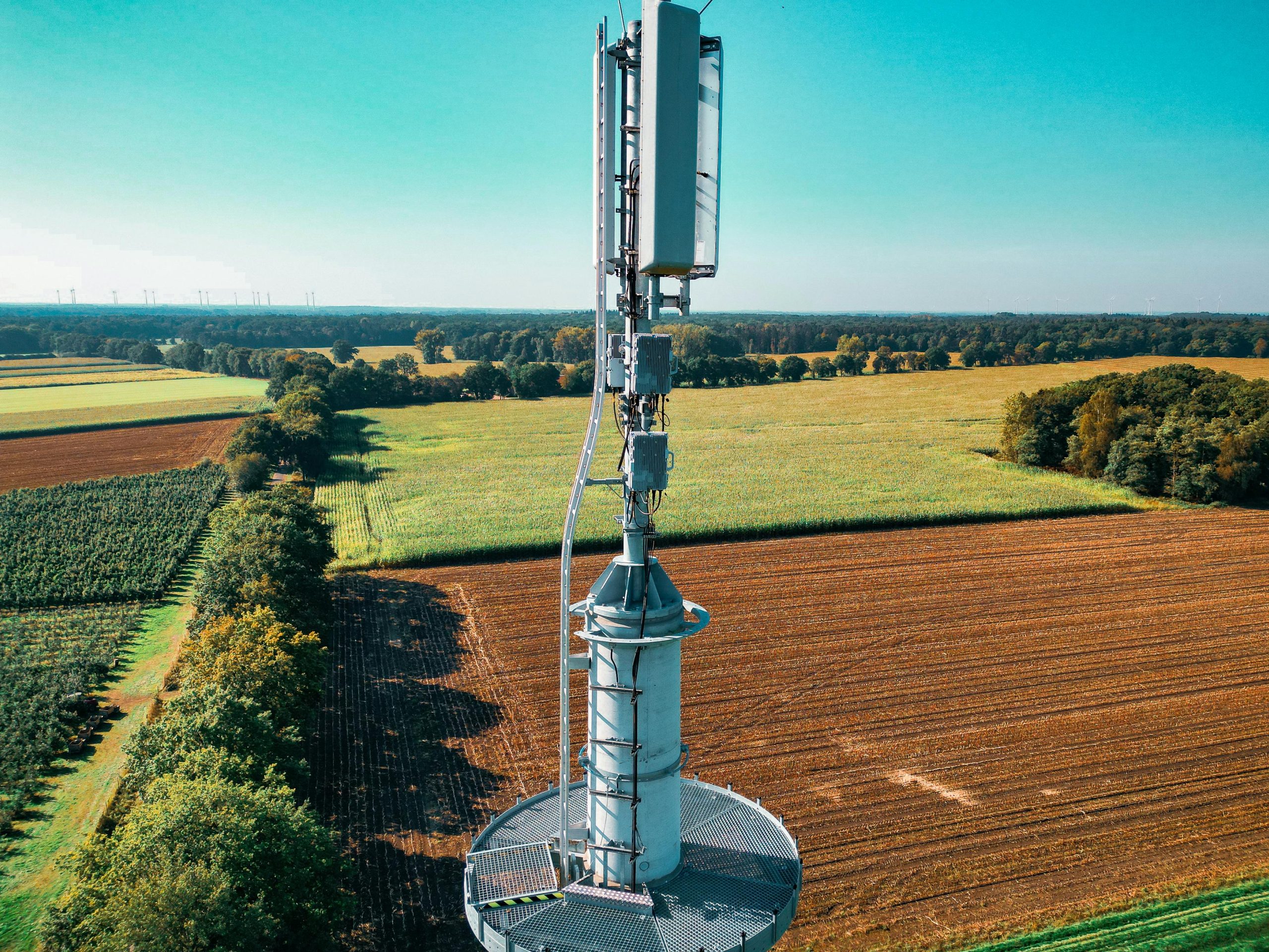 Aerial view of a cell tower amidst vibrant farmland, symbolizing technology and nature coexistence.