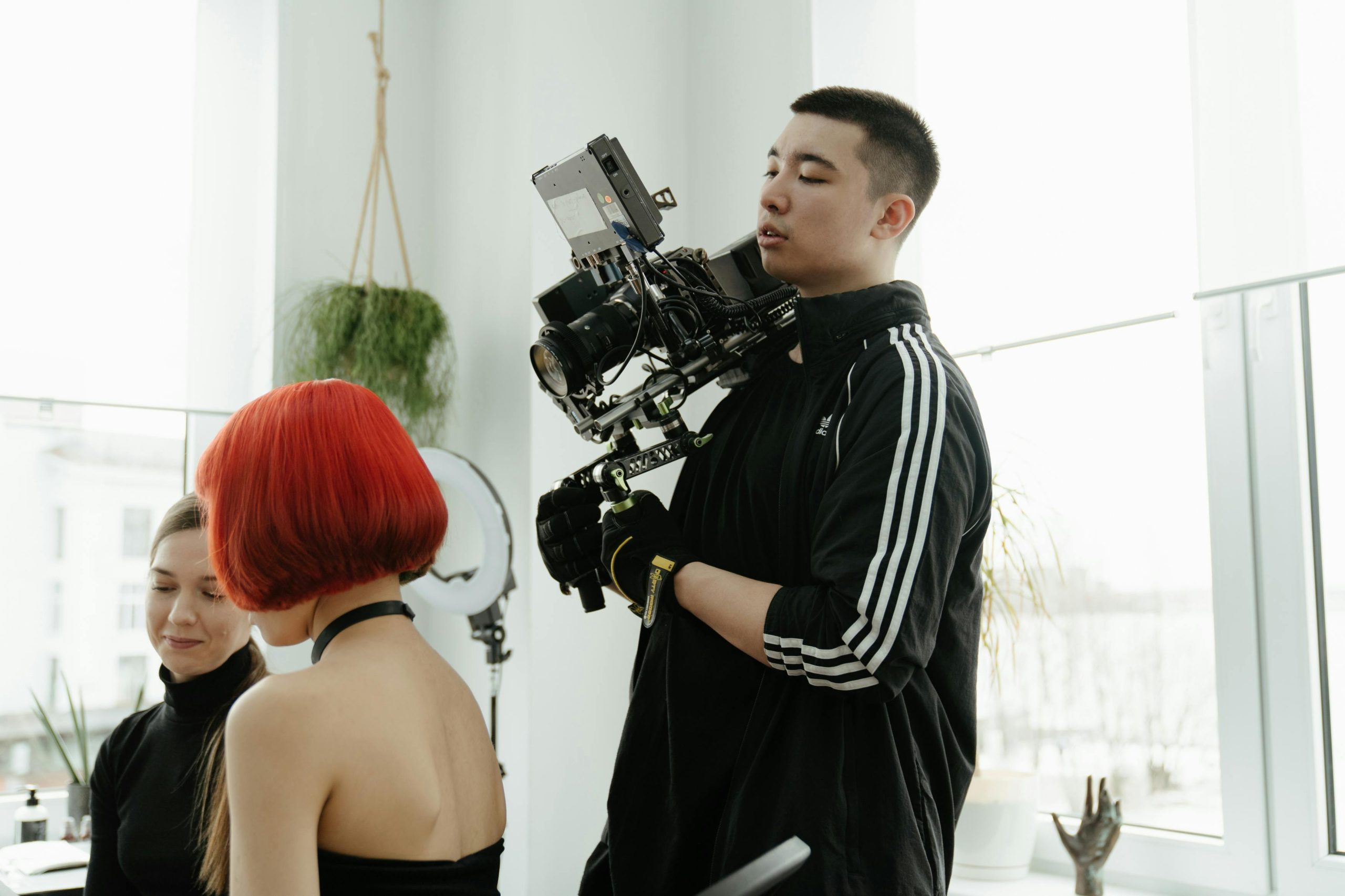 A young Asian camera operator filming during a creative production indoors.