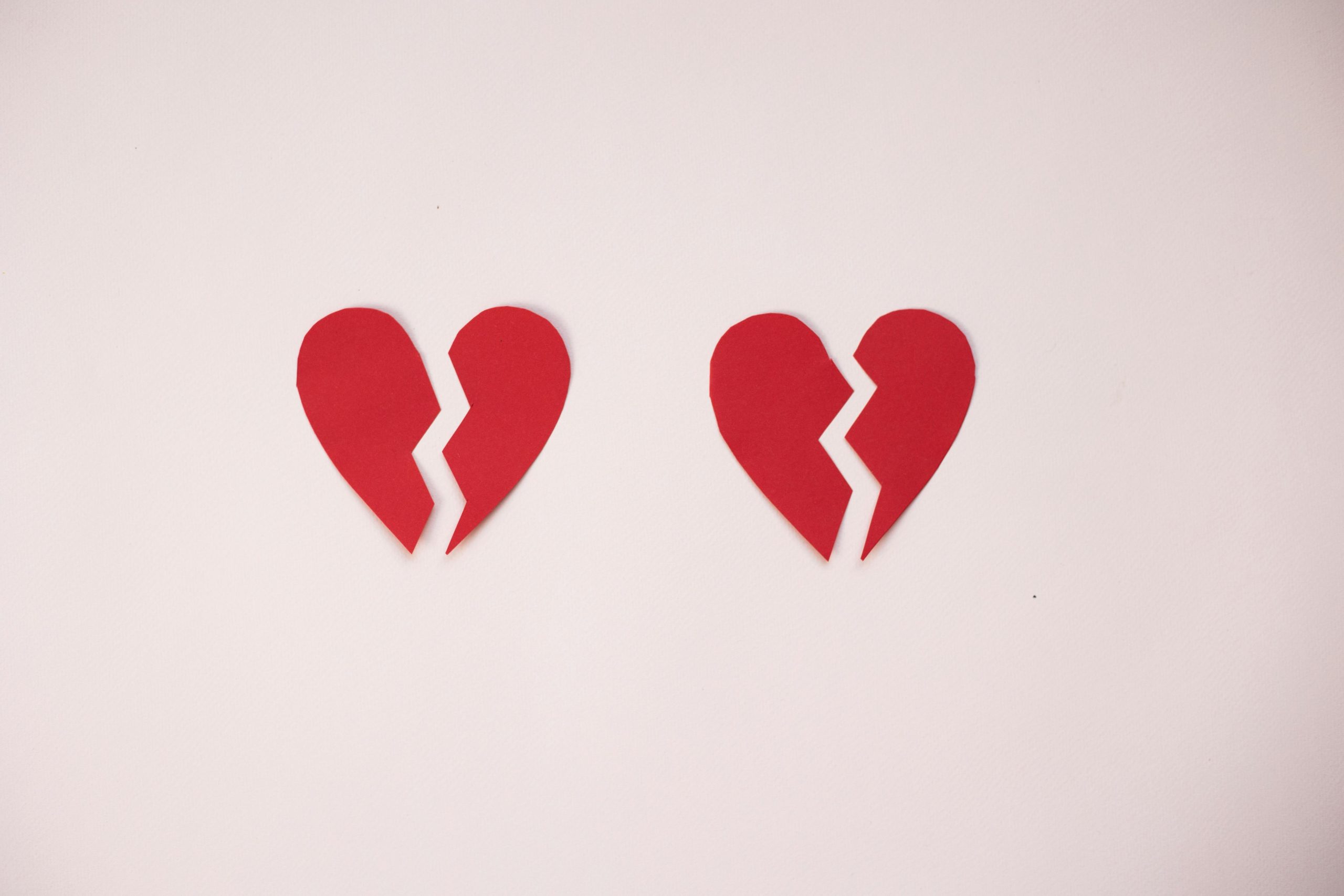 Two red broken heart shapes on a white background symbolizing heartbreak or separation.