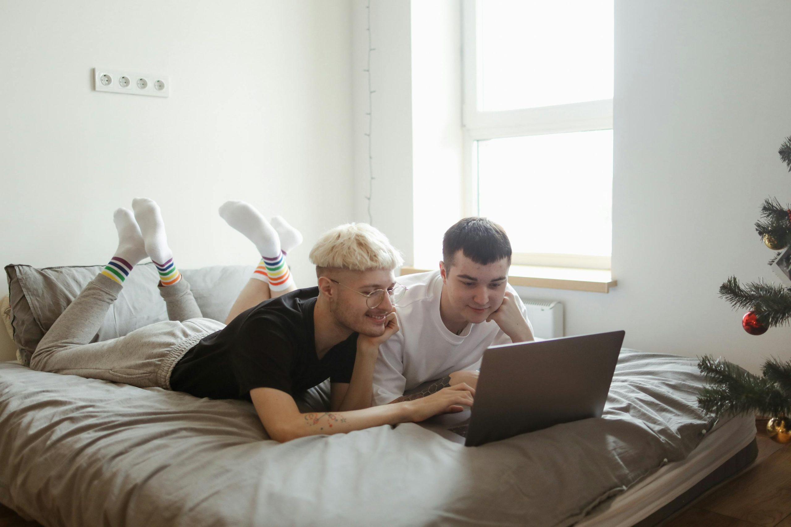 Two adults lying on a bed using a laptop, emphasizing connection and relaxation.