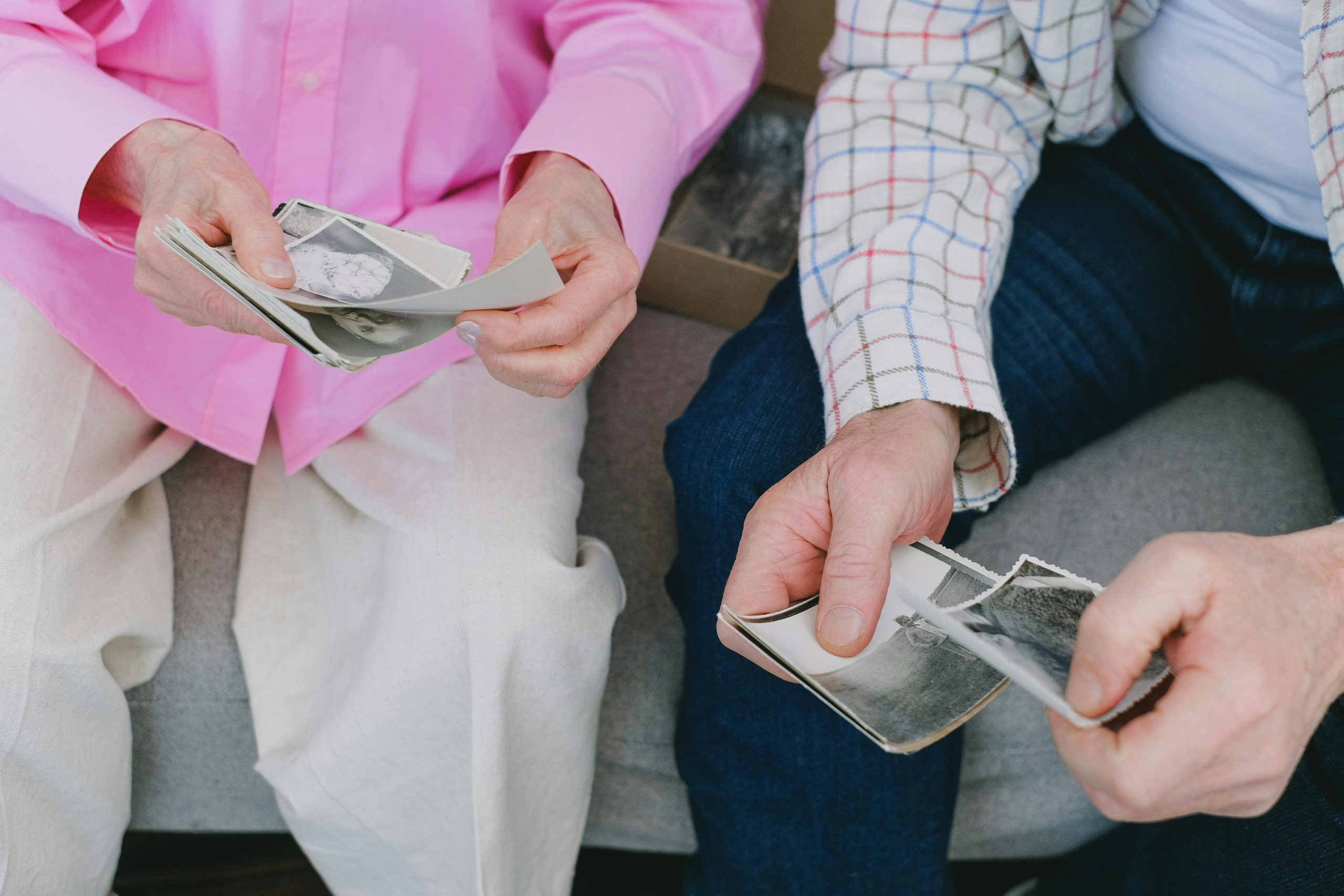 Senior couple reminiscing over vintage photographs, sharing memories.