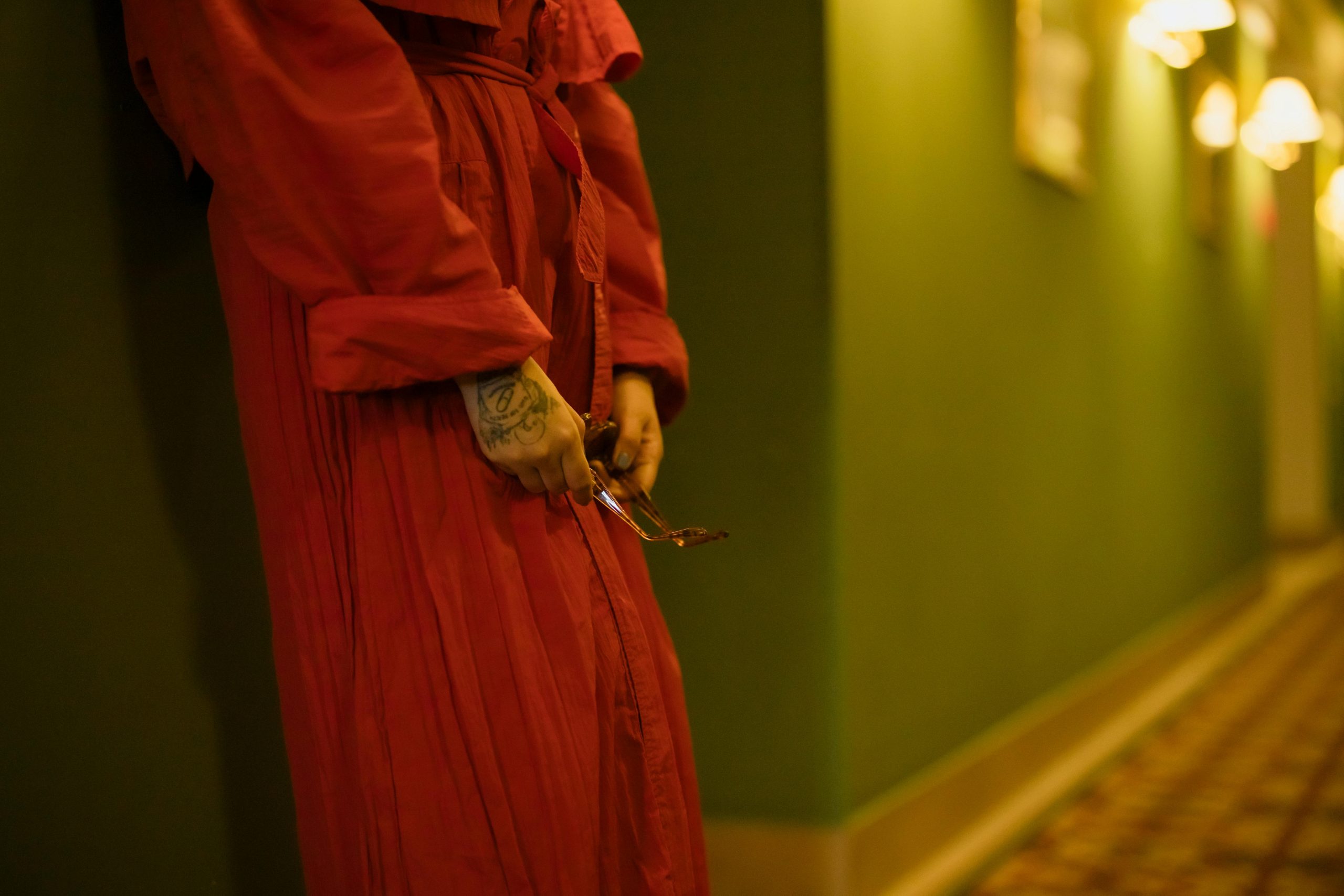 Stylish woman in a red dress standing in a hotel corridor, creating an elegant atmosphere.