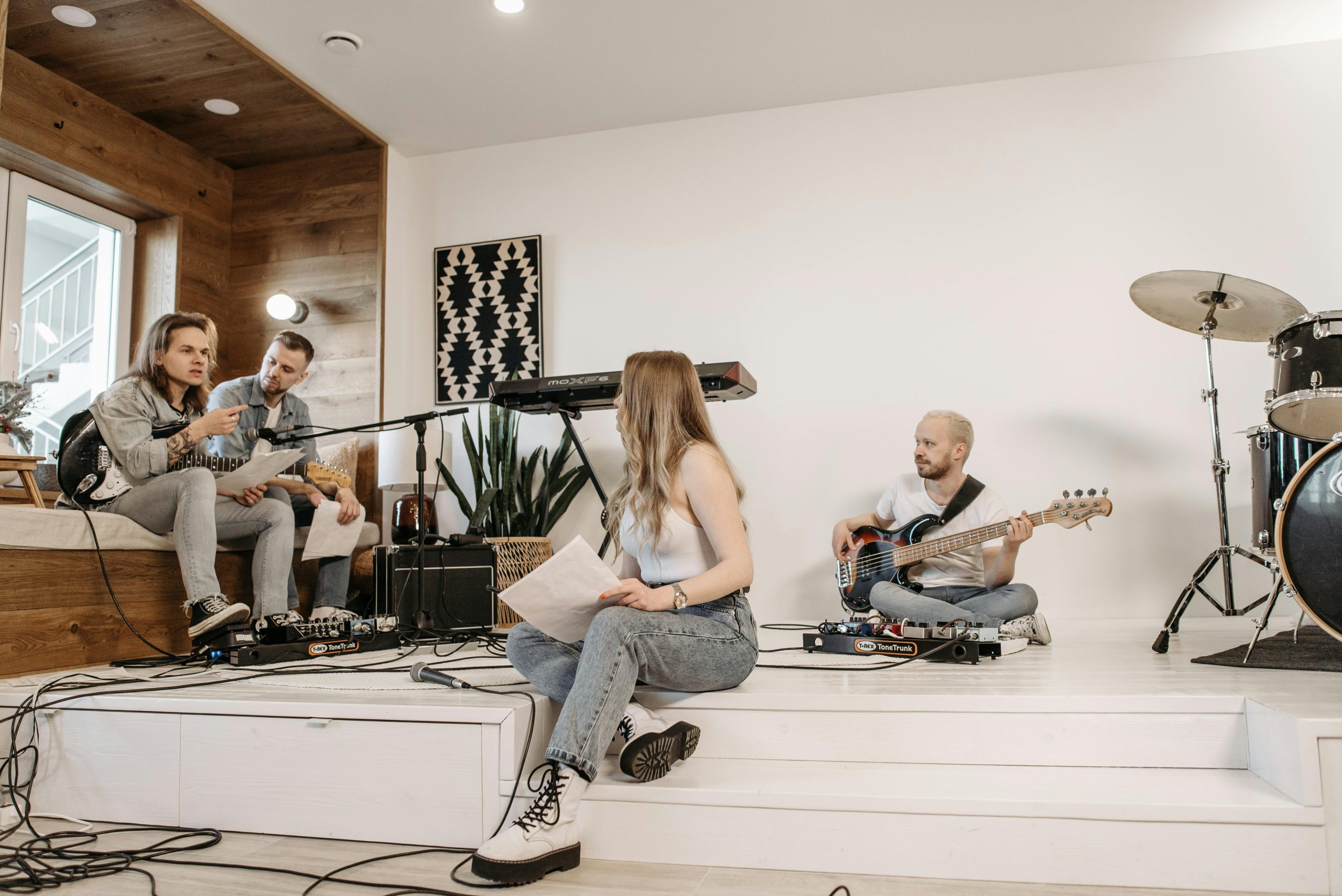 A group of young musicians rehearsing with instruments in a modern studio setting.