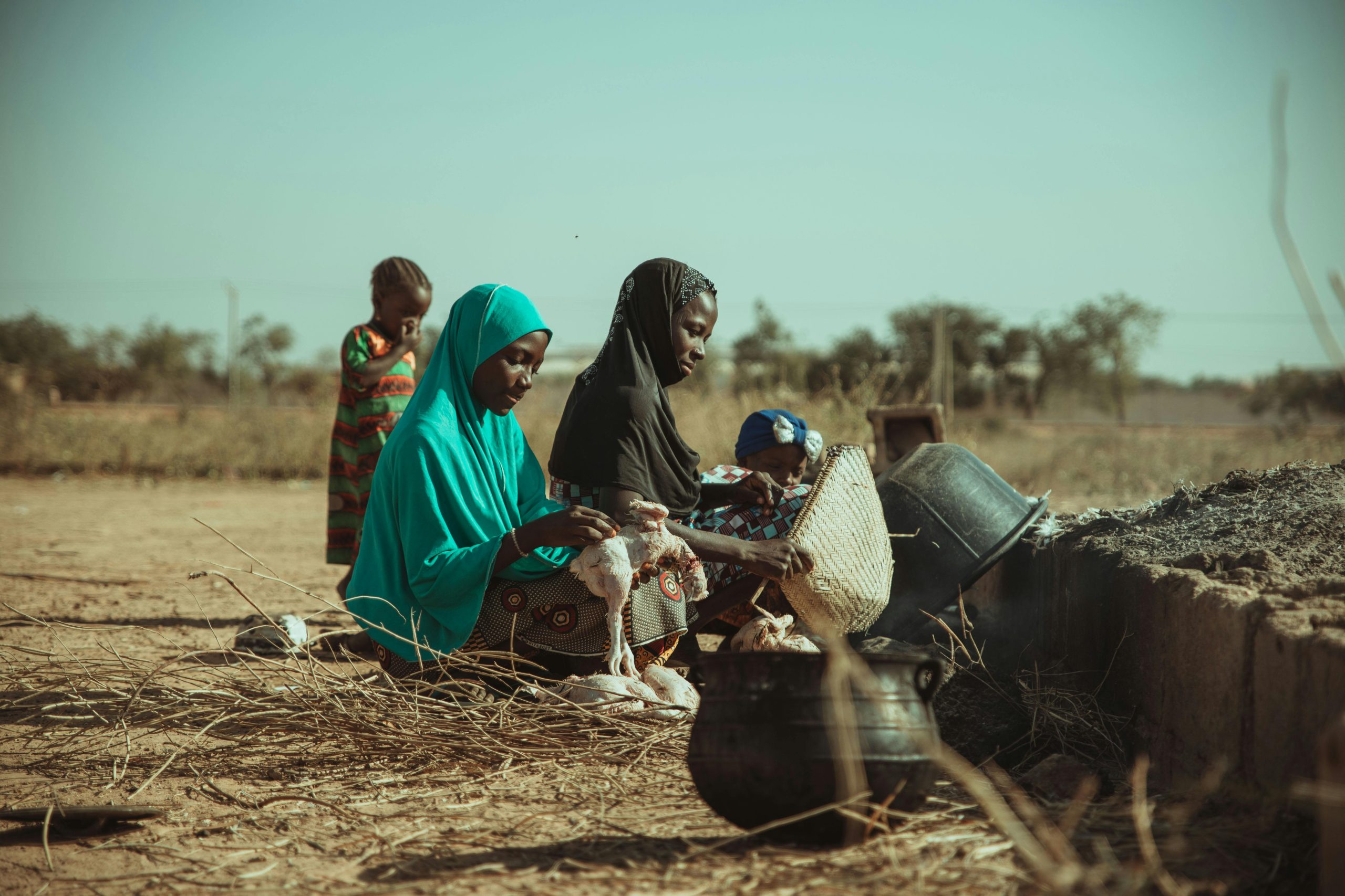 Women preparing chickens outdoors, showcasing rural life and community involvement.